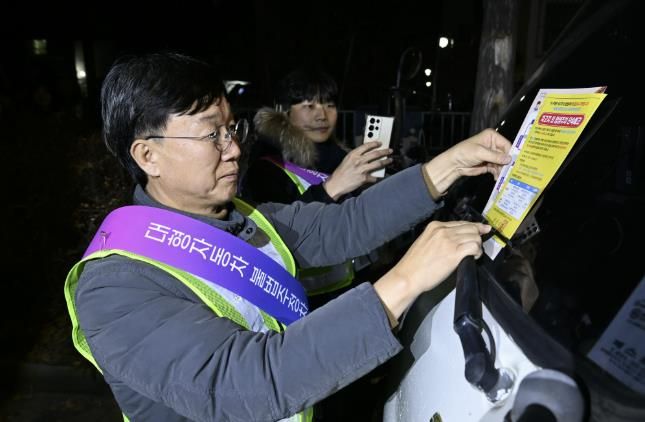 이민근 안산시장이 20일 새벽시간, 단원구 와동 일대에 불법 밤샘주차된 대형차랑에 계도문을 부착하고 있다.